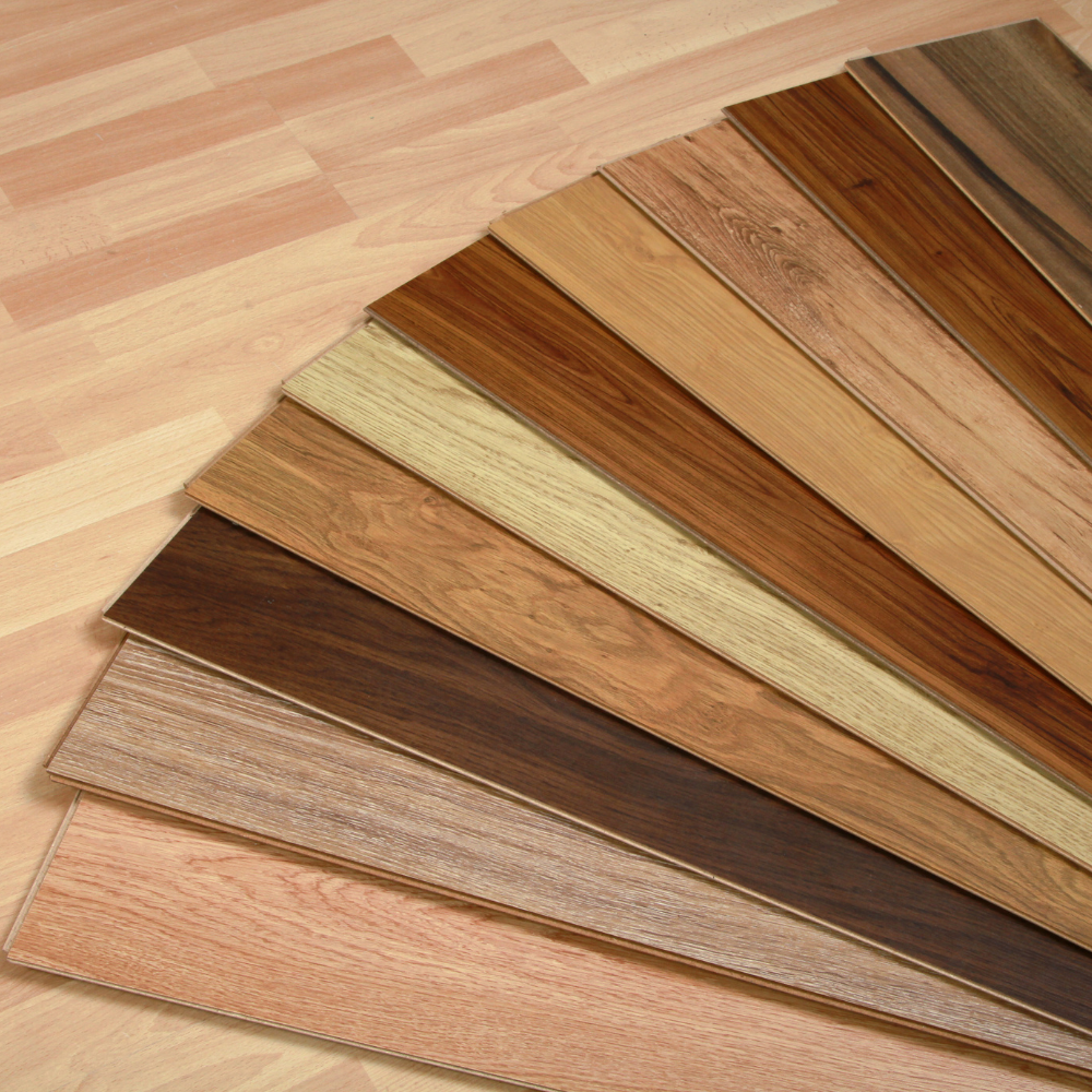 A selection of wooden flooring samples laid out in a fan-like arrangement, showing a variety of wood grain patterns and colors.